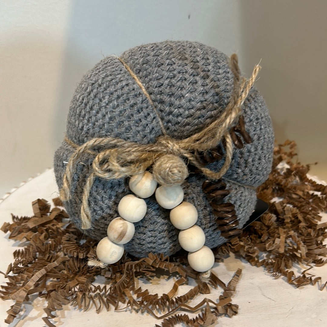 Gray knitted pumpkin with wooden beads and twine for a stem.