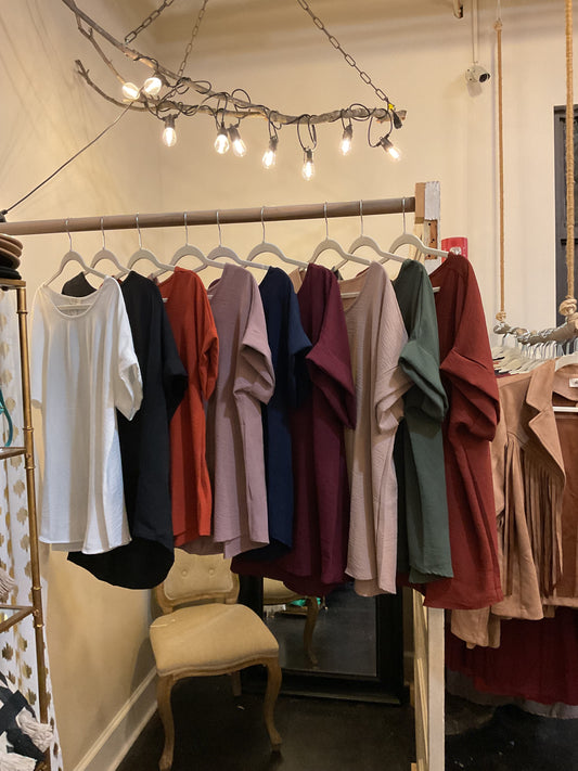 Assorted scoop-neck top featuring permanent rolled sleeve detail and an asymmetrical hem.