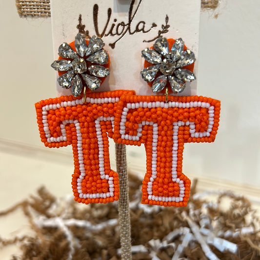 "T" orange dangling earrings with bejeweled flower studs.