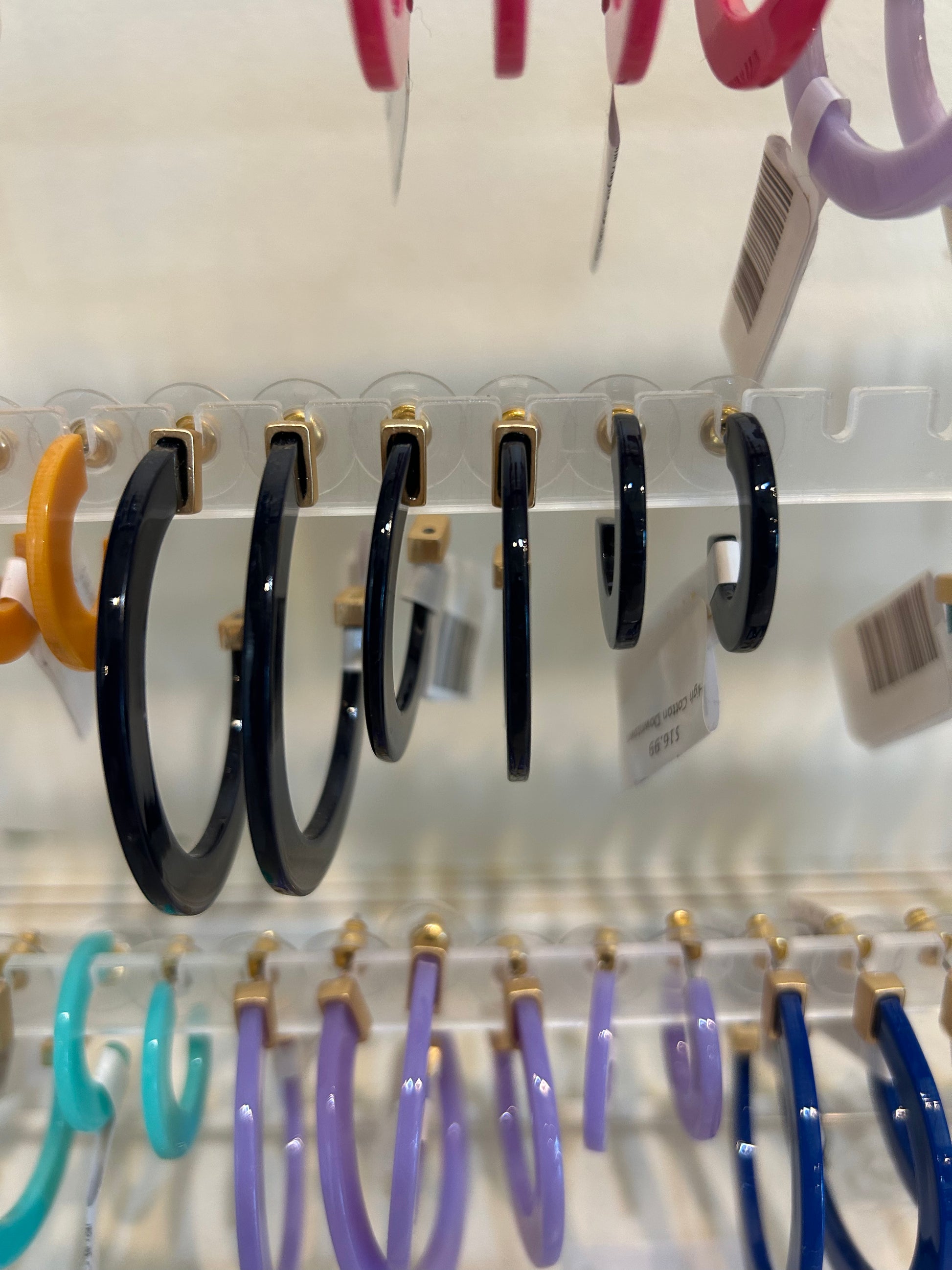 Black acrylic hoop earrings in three sizes.