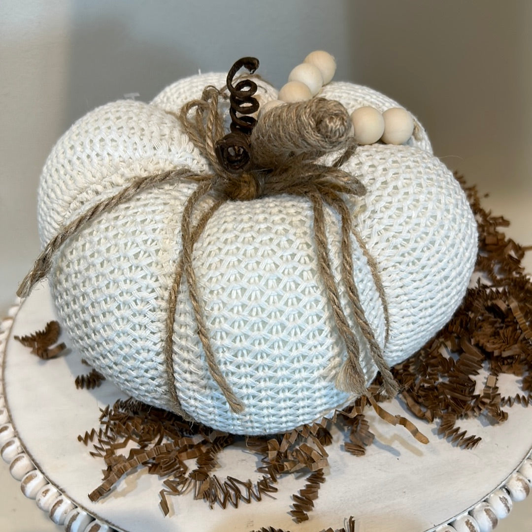 White knitted pumpkin with wooden beads and twine for a stem.