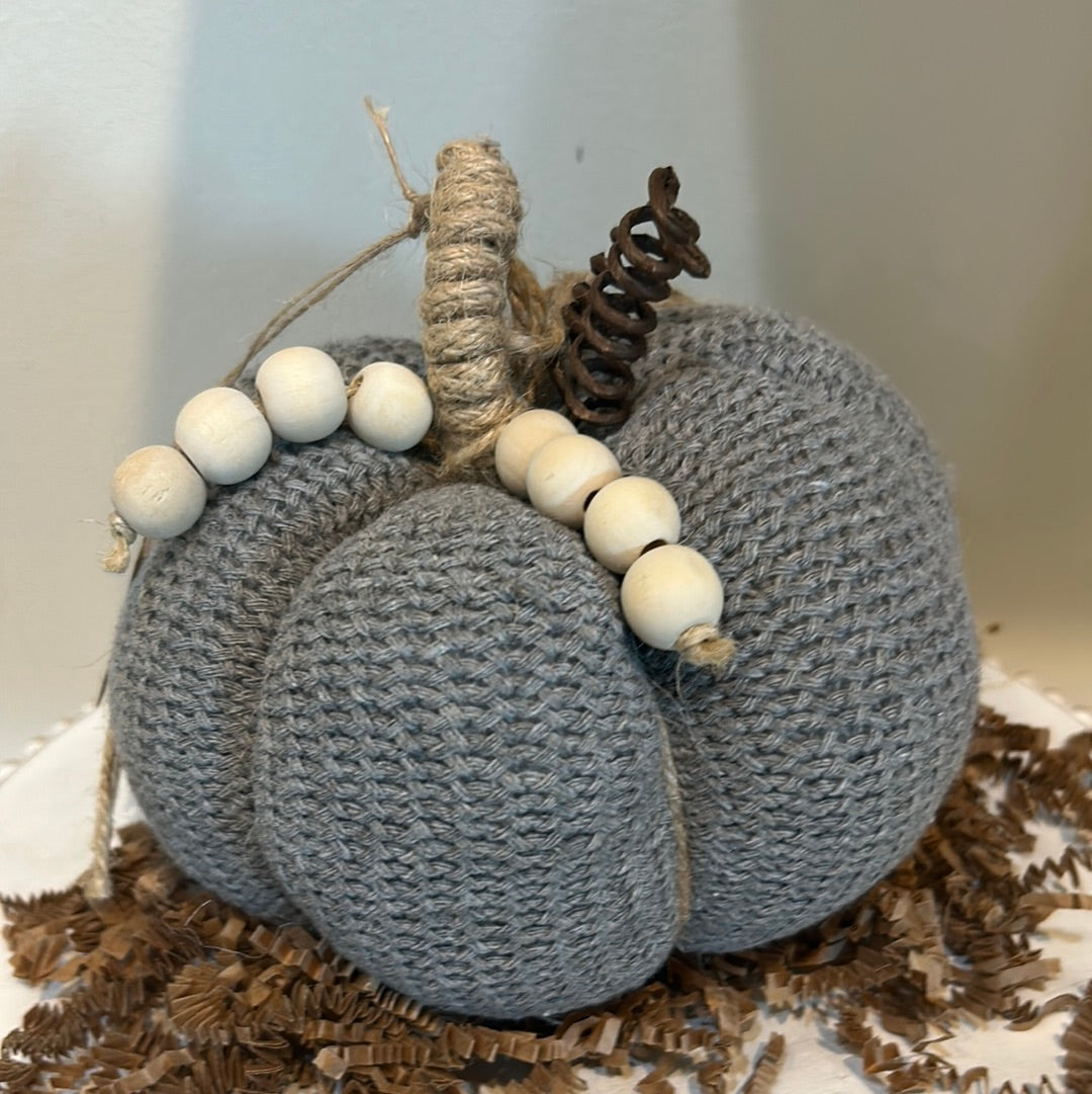 Gray knitted pumpkin with wooden beads and twine for a stem.