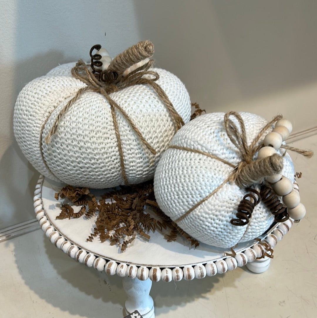 White knitted pumpkins with wooden beads and twine for a stem.