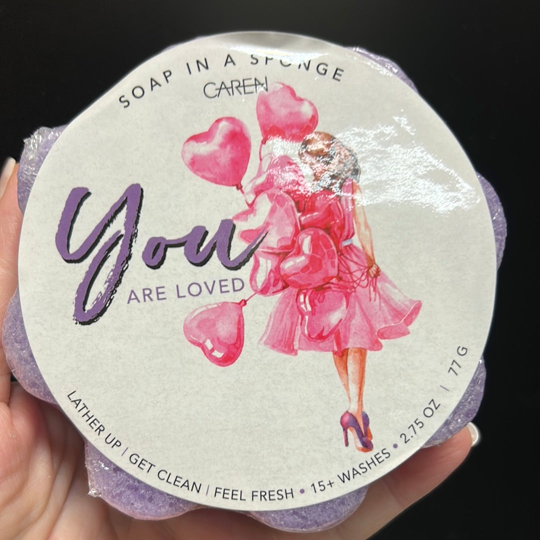 Caren "You are loved" soap sponge shaped like a purple flower.