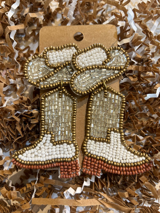Beaded dangling earrings in the shape of cowboy hats and boots with gold and white beads.