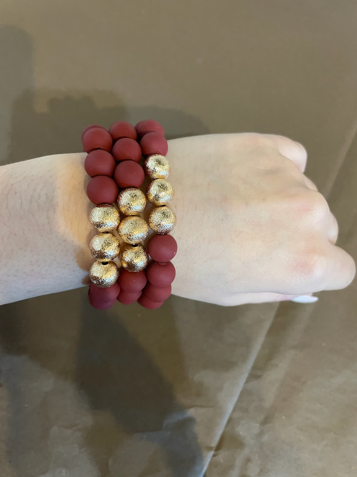 Maroon clay textured bracelet stack with golden beads.
