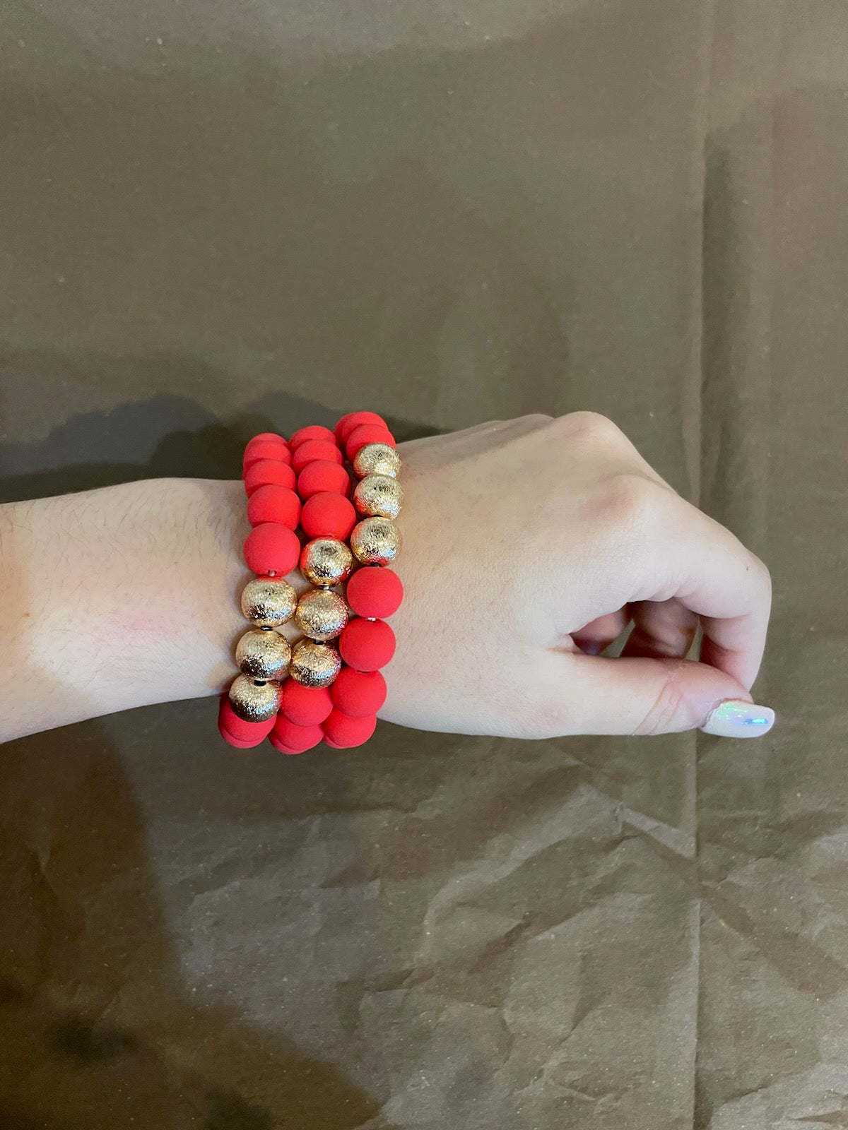 Red clay textured bracelet stack with golden beads.