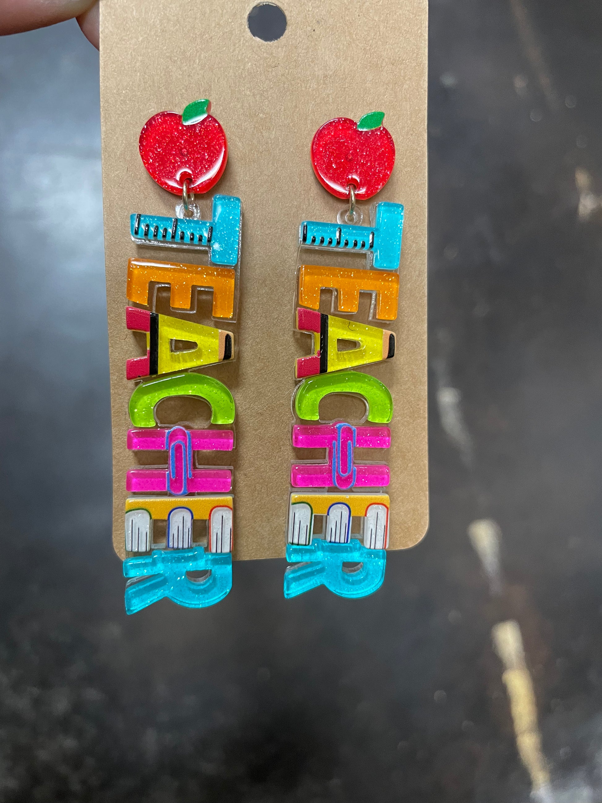 Dangle earrings featuring "TEACHER" in bright colors.
