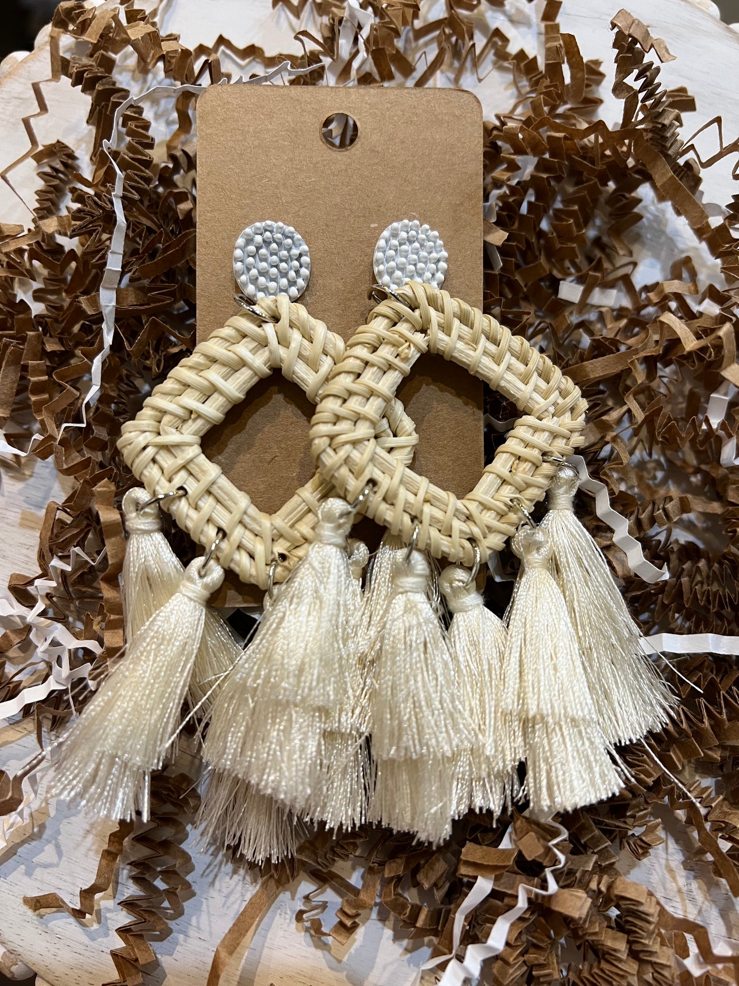Tan square raffia earrings with white tassels.