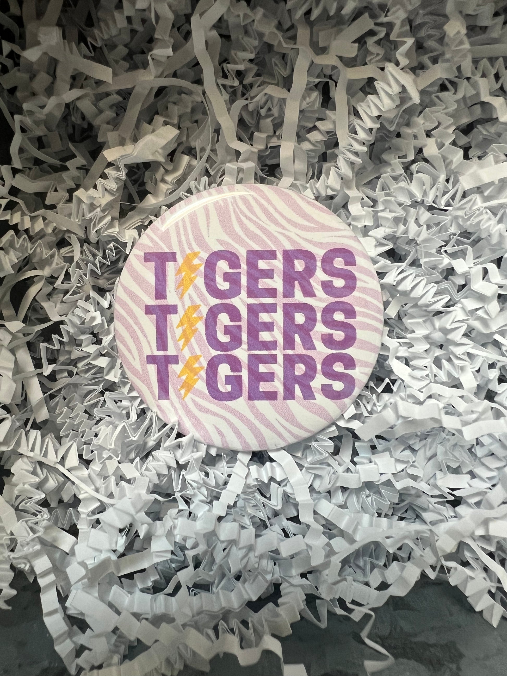 LSU button with purple tiger stripe background featuring "TIGERS" with the "I" as a lightning bolt.
