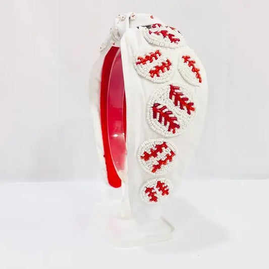 White headband with topknot and beaded baseballs.