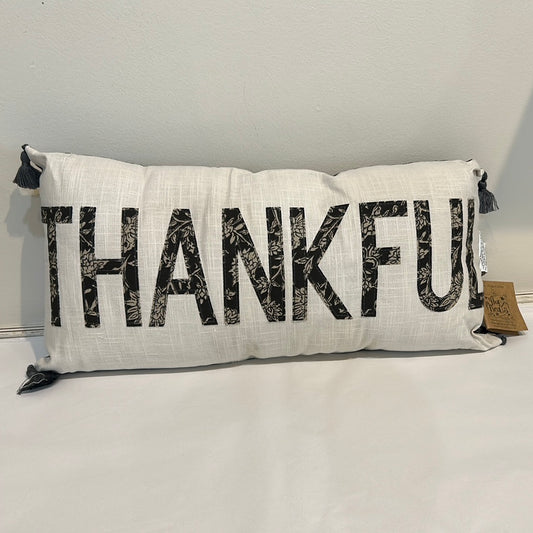 White, long pillow with "Thankful" in black floral fabric.