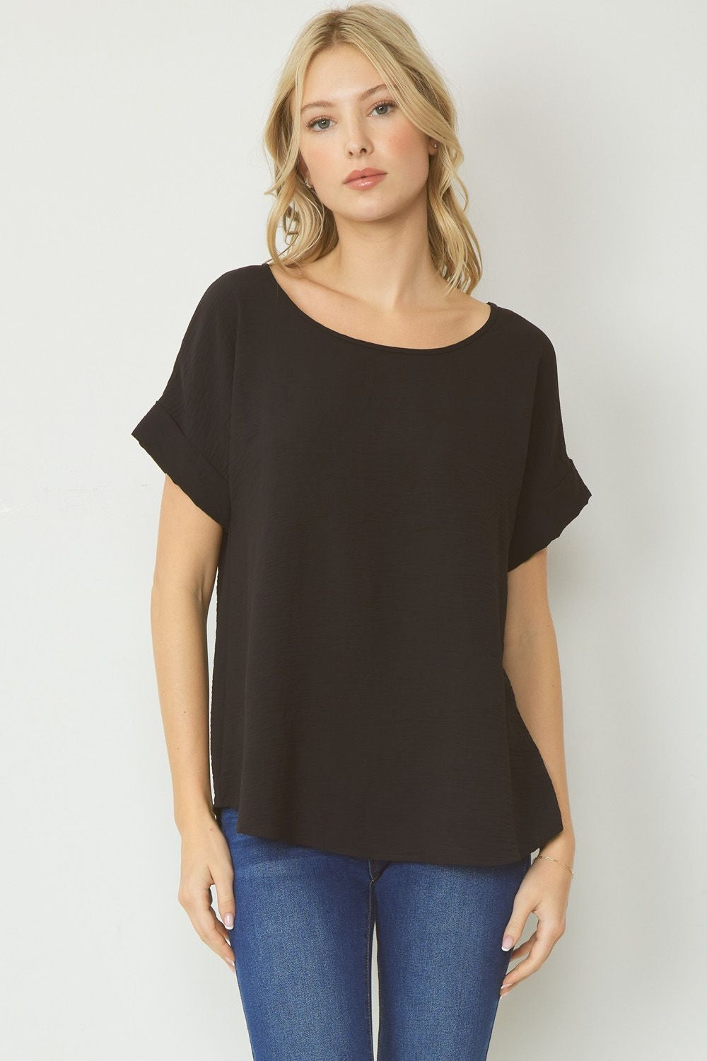 Black scoop-neck top featuring permanent rolled sleeve detail and an asymmetrical hem.