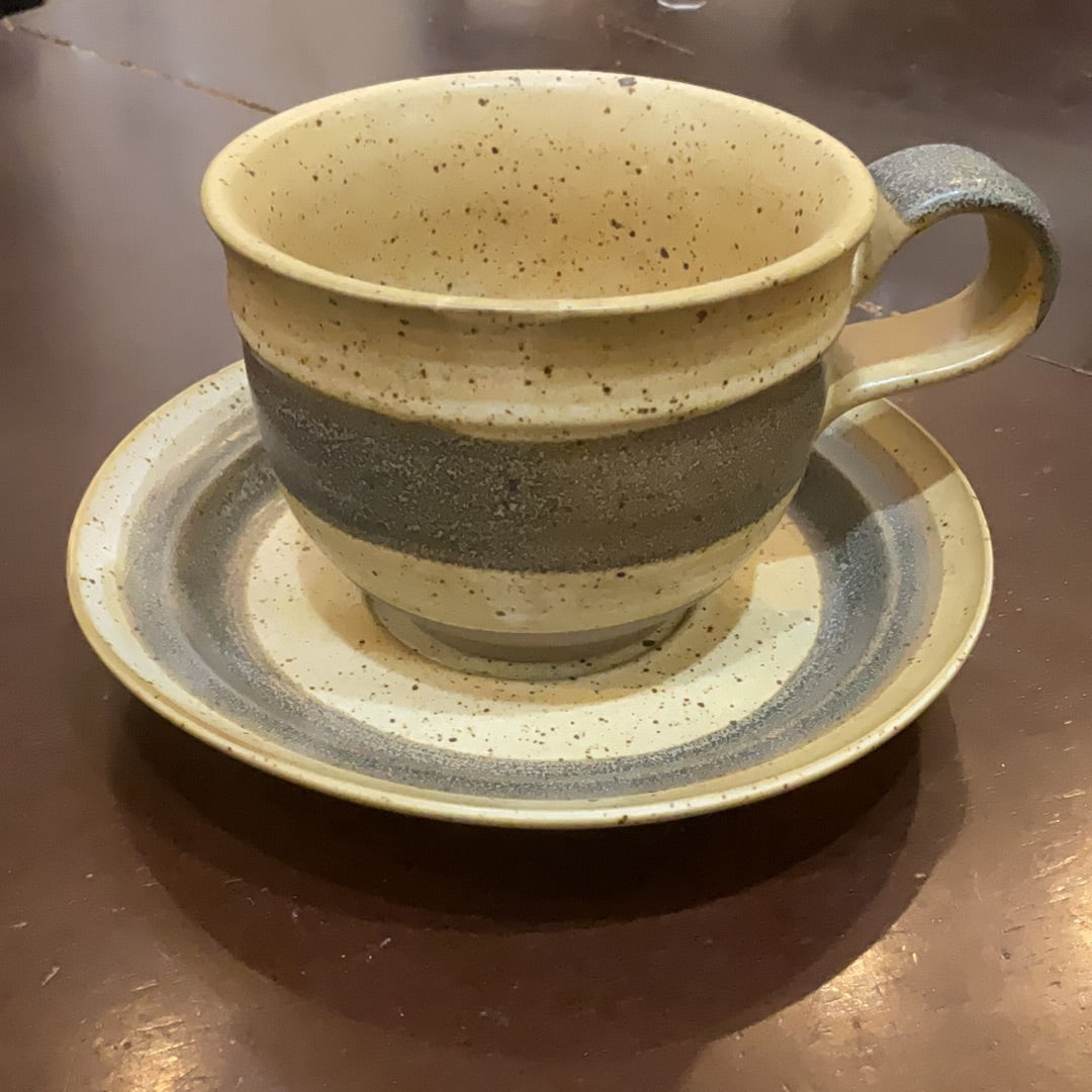 White and gray speckled mug and saucer set.