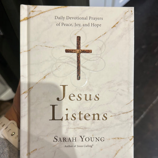 Book with white and gold marble cover with cross featuring "Daily Devotional Prayers of Peace, Joy, and Hope; Jesus Listens; Sarah Young".