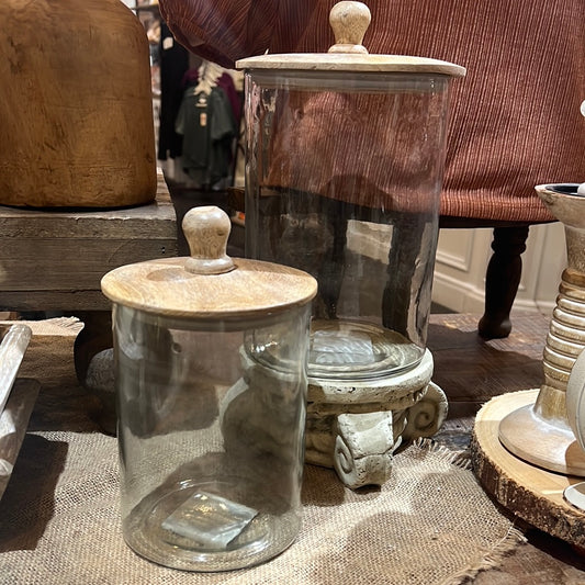 Assorted clear glass canisters with wooden lids.