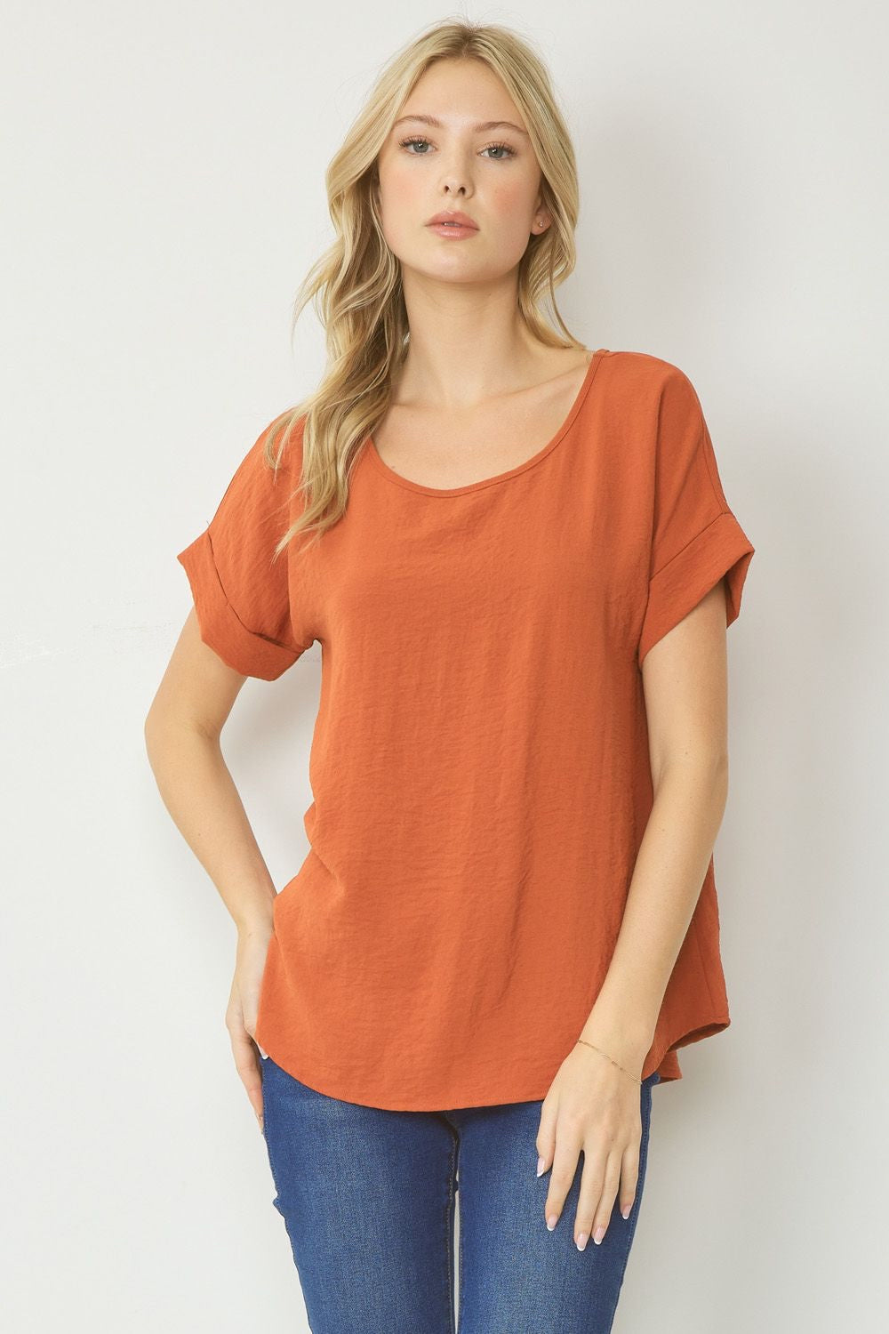 Rust scoop-neck top featuring permanent rolled sleeve detail and an asymmetrical hem.