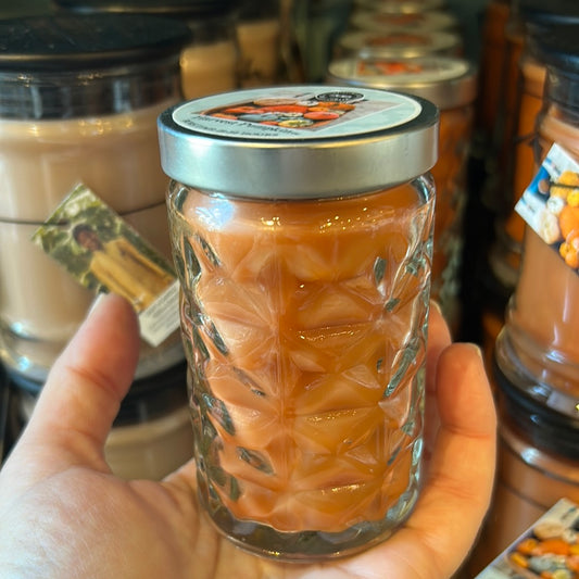 Orange candle in a glass jar with lid.