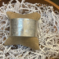 Wide silver in color bangle.