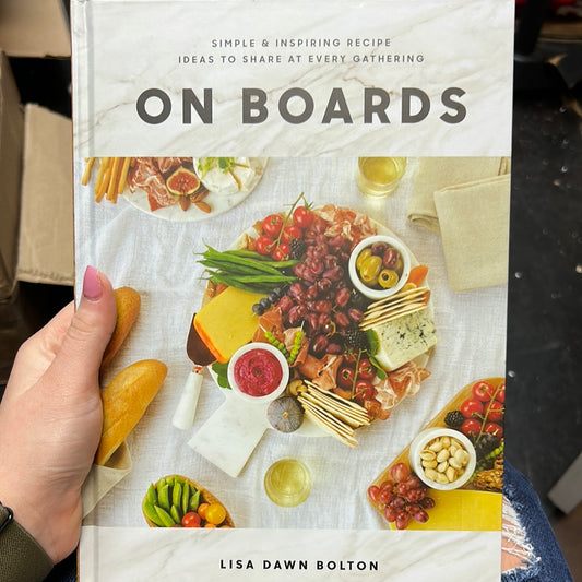 White book with charcuterie board titling "ON BOARDS; Simple & inspiring recipe ideas to share at every gathering".