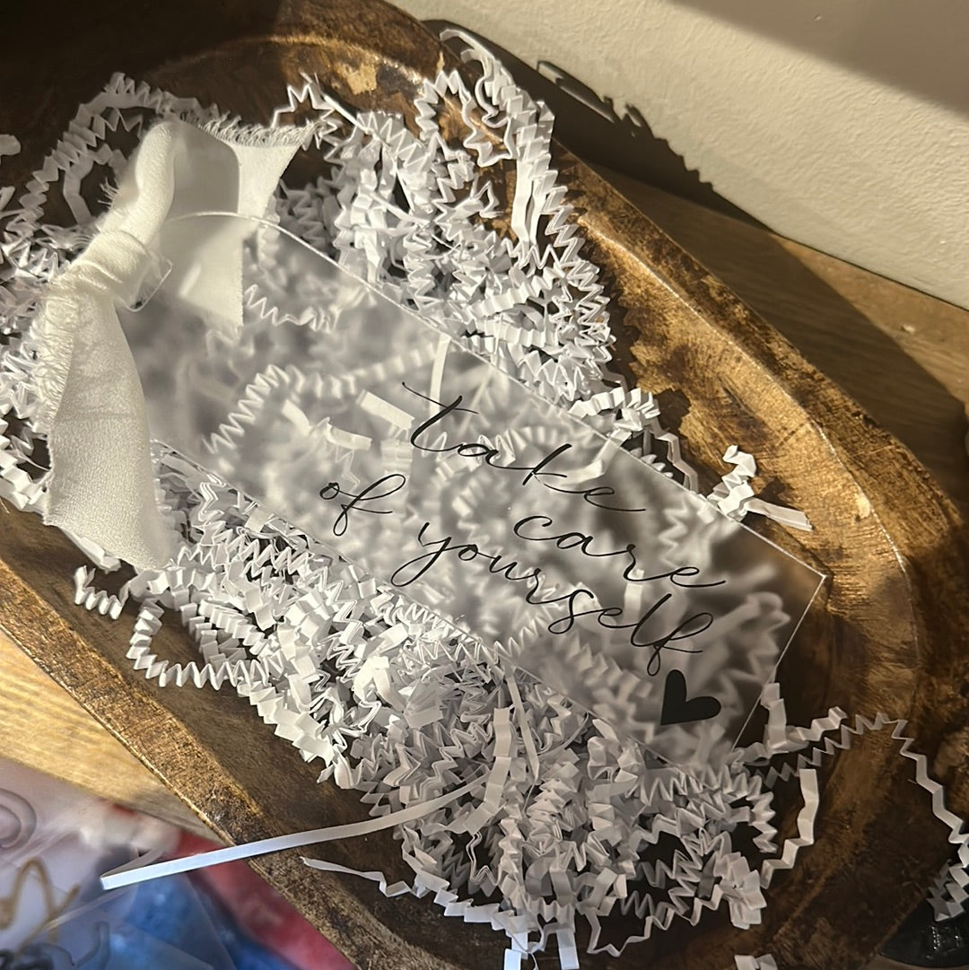 Clear acrylic bookmark with black lettering featuring "take care of yourself".