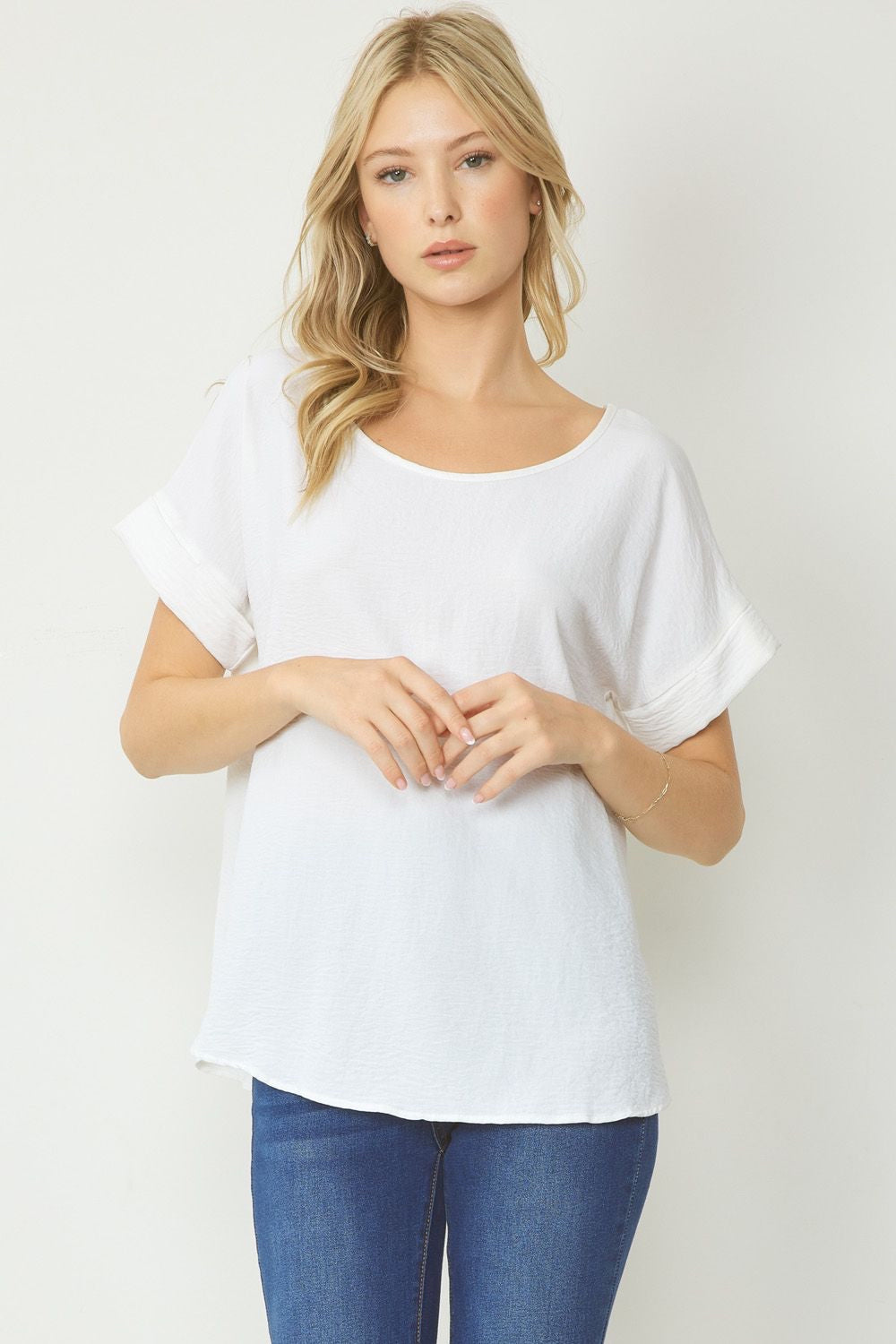 White scoop-neck top featuring permanent rolled sleeve detail and an asymmetrical hem.