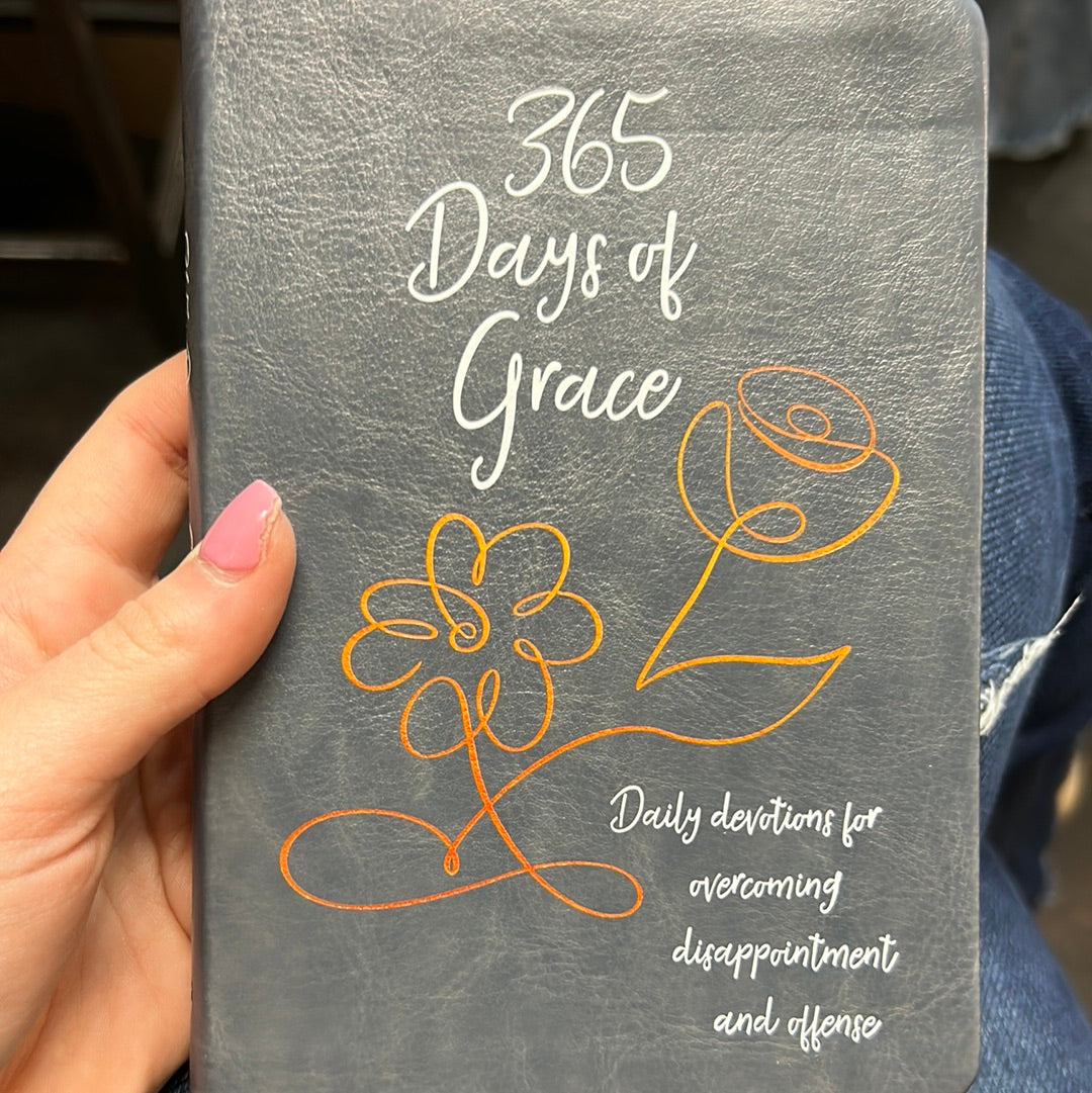 Book with a black cover and white lettering displaying "365 Days of Grace; Daily devotions for overcoming disappoint and offense", with a depiction of flowers in gold.