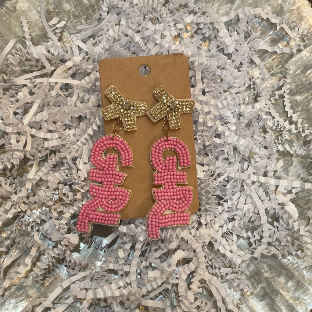 Pink beaded earrings featuring "GIRL" dangle with tan beaded bows.