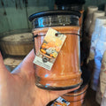 Orange Harvest Pumpkin candle in small jar with black lid.