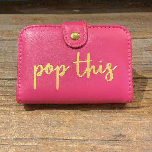 Pink pill box with button clasp featuring "pop this" in golden lettering.