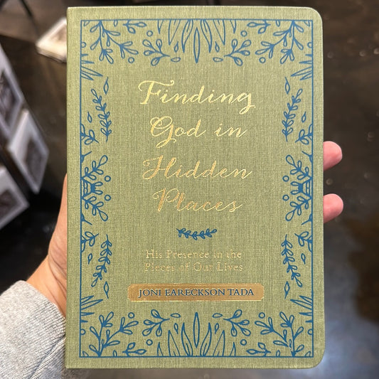 Book displaying "Finding God in Hidden Places" in gold lettering on a light green background with blue floral patterns.