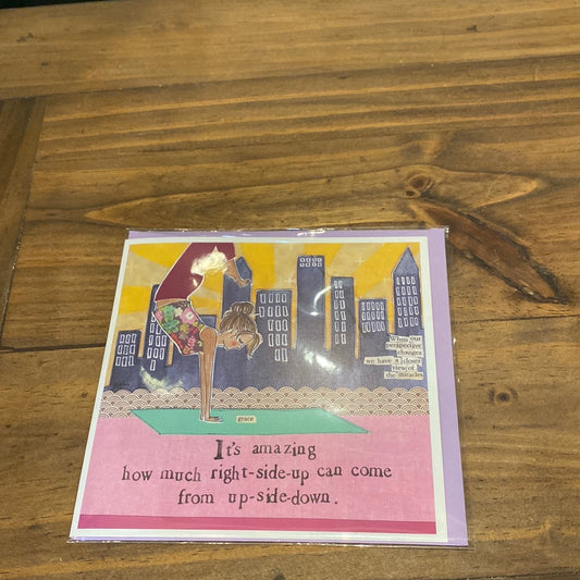 Card with woman doing yoga and city skyline featuring "It’s amazing how much right side up can come from up-side down.”