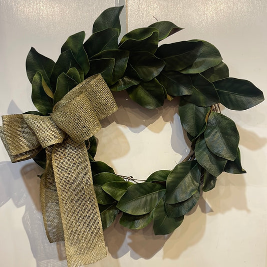 Wreath made of magnolia leaves with a burlap bow.