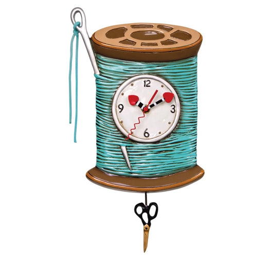Clock shaped like needle and blue thread with scissors.