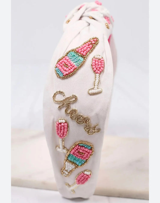  White topknot pheadband with pink and blue bottles/glasses with "Cheers" in gold.