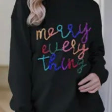 Model featuring black "Merry Everything" sweater with colorful stitching.