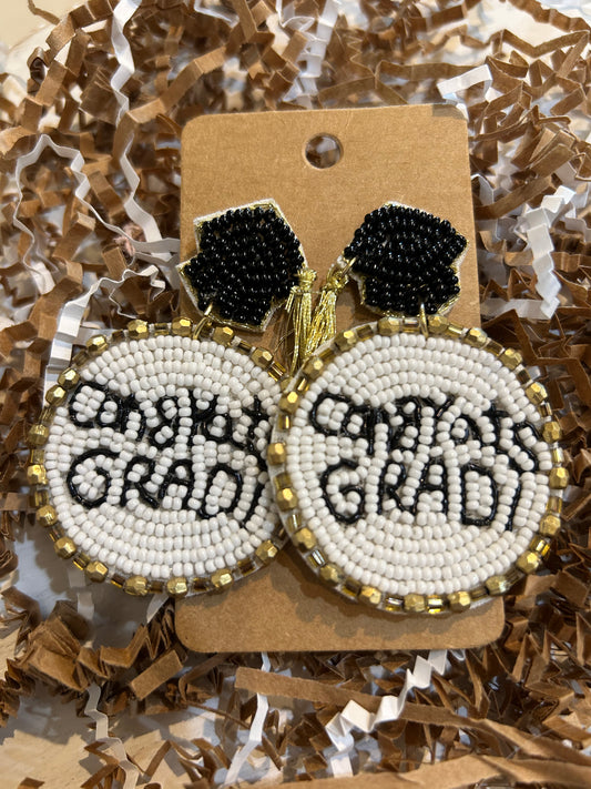 Beaded dangle earrings with "Congrats Grad!" with black lettering on white background and gold trim, and black beaded graduation caps as studs.