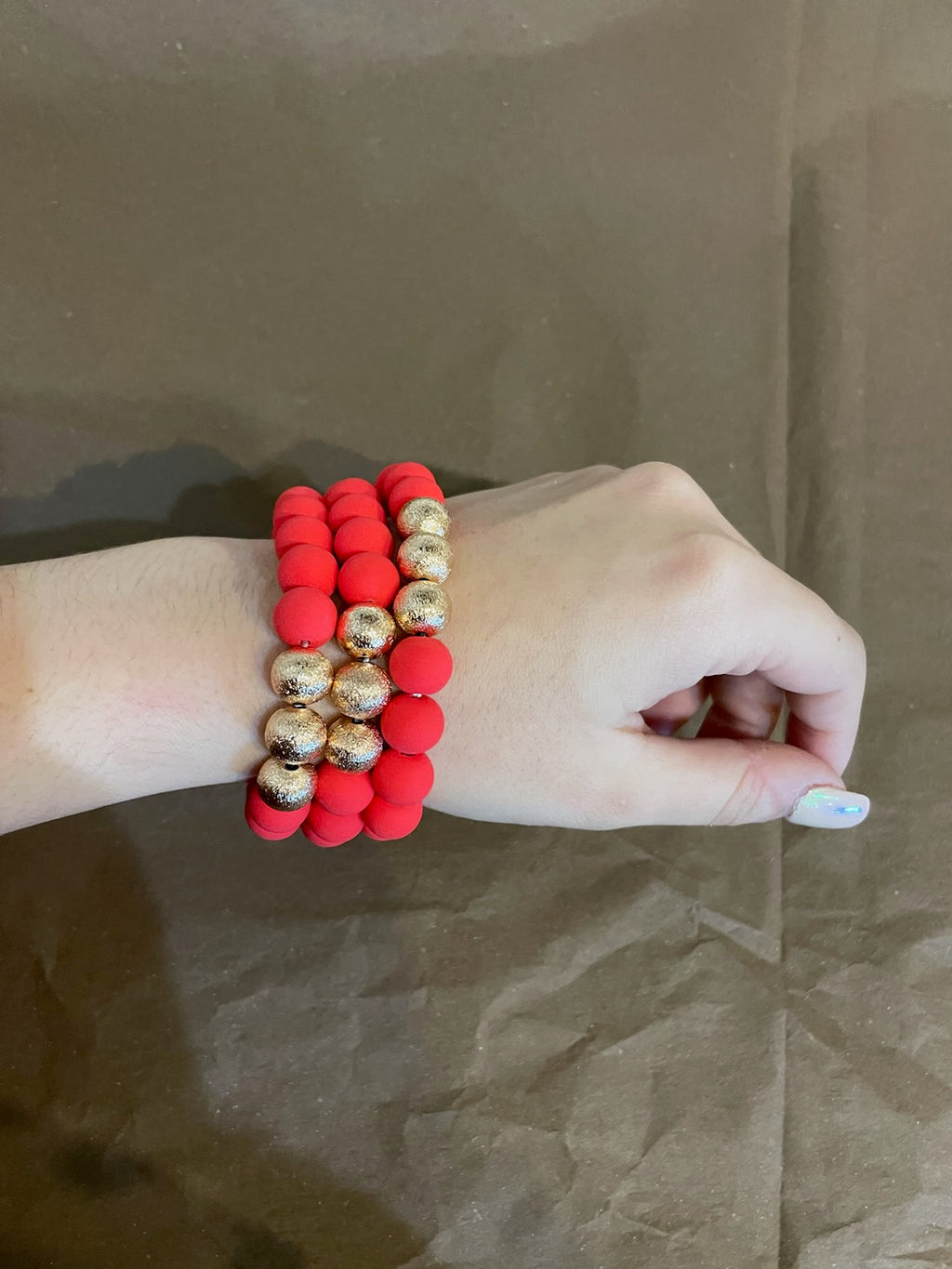 Red clay textured bracelet stack with golden beads.