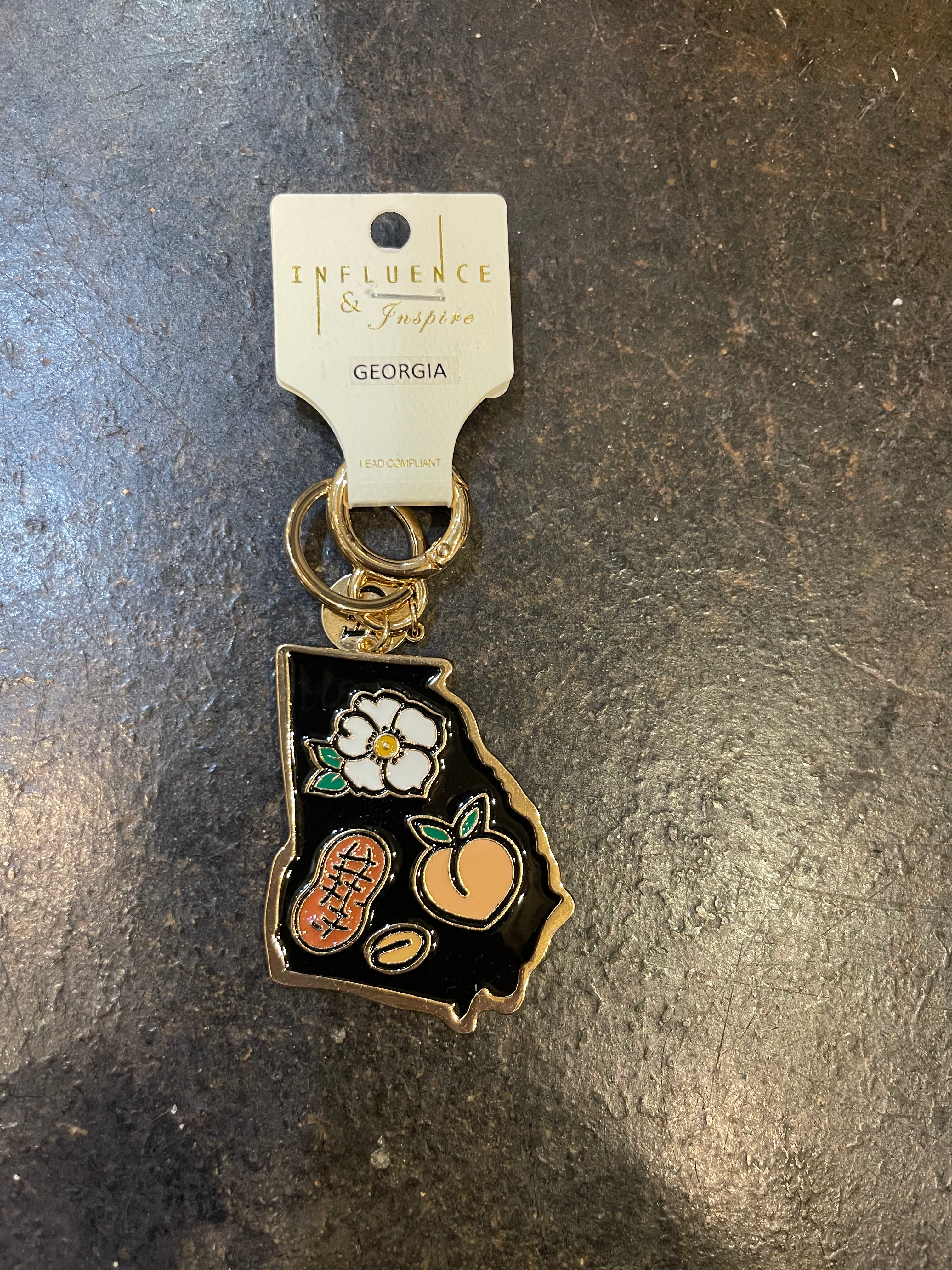 Keychain in the shape of Georgia with a black background and golden trim, featuring iconic symbols of Georgia.