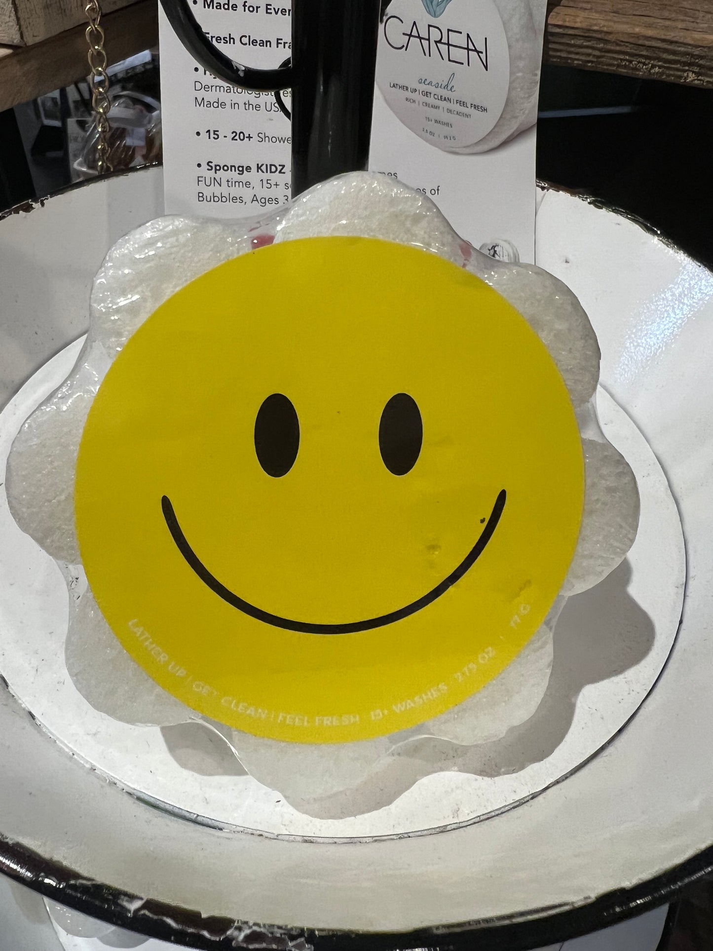 Caren smiley face soap sponge shaped like a white flower.