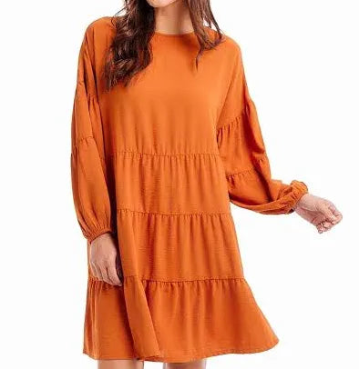 Burnt orange, long sleeved, mid-length tiered dress.