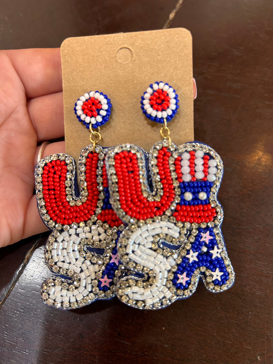 Beaded, sparkly dangle earrings featuring "USA" with a top hat in red, white, and blue beading.