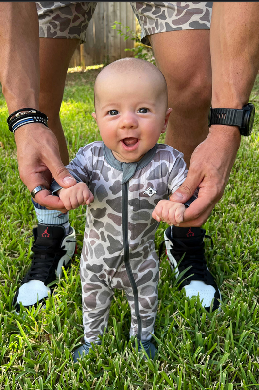 Baby model featuring a camo, zip-up onesie.